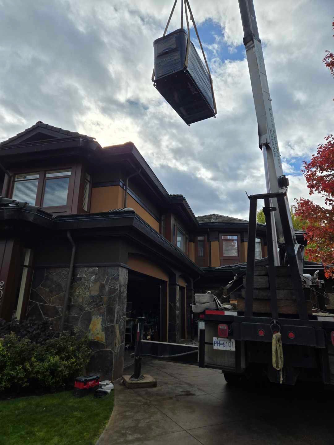 Crane lifting equipment over a Kelowna home during an installation
