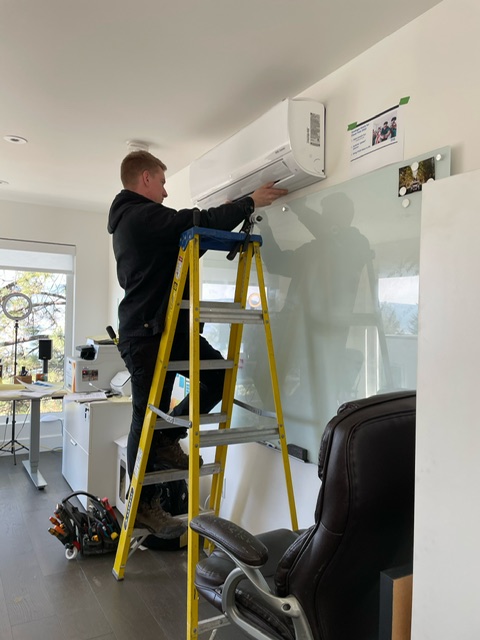 Technician installing a ductless heat pump head inside an Okanagan home