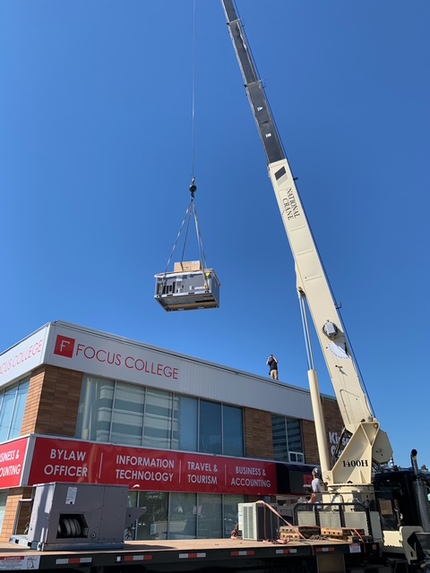 Crane lifting a packaged rooftop unit onto a commercial building in Kelowna