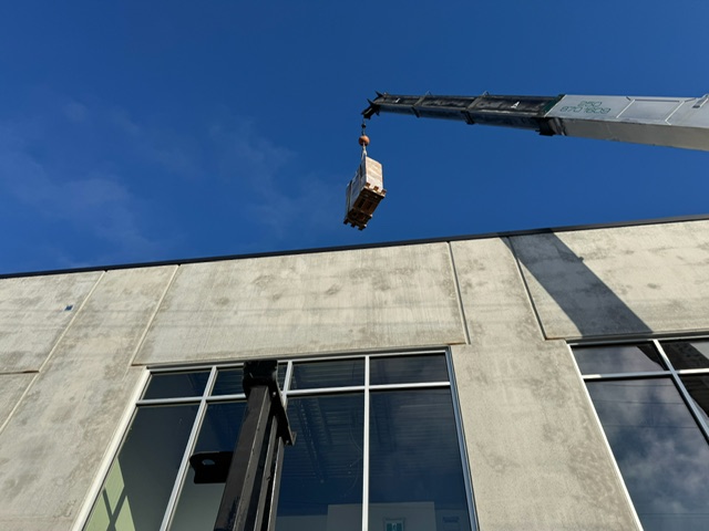 Rooftop unit being craned onto a commercial building in the Okanagan